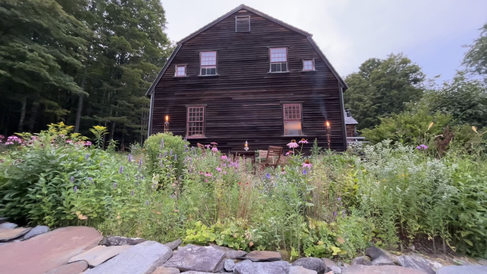Barn and wildflower garden with torches lit at dusk